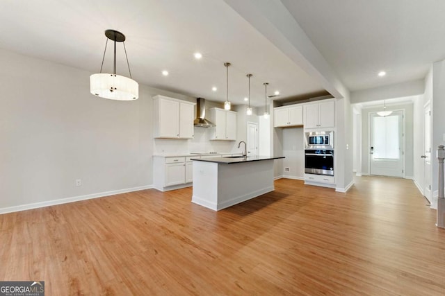 kitchen with light wood-style flooring, a sink, appliances with stainless steel finishes, and wall chimney exhaust hood