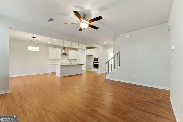 unfurnished living room featuring baseboards, light wood-style floors, ceiling fan, and visible vents