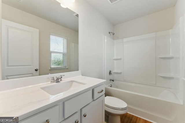 full bathroom with visible vents, toilet, wood finished floors, vanity, and shower / washtub combination