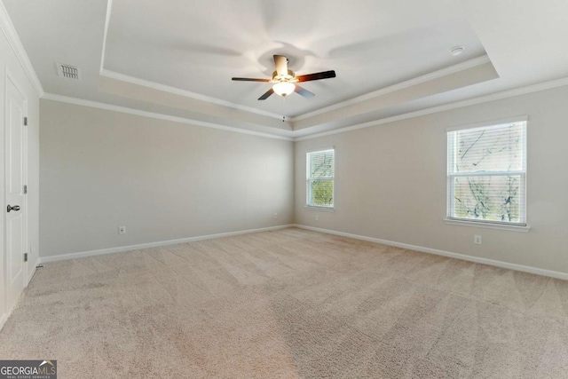 spare room featuring a tray ceiling, visible vents, carpet flooring, and a ceiling fan