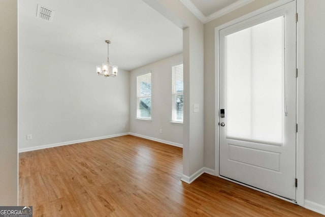foyer with baseboards, visible vents, a notable chandelier, and wood finished floors
