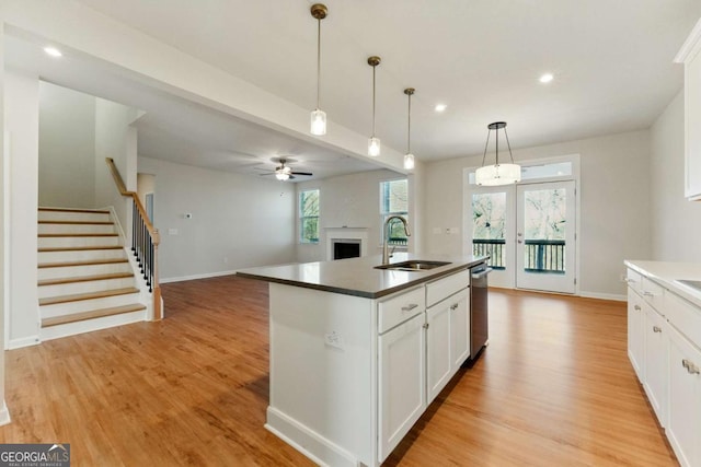 kitchen with open floor plan, a sink, light wood-style floors, white cabinets, and a fireplace