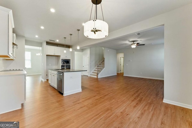 kitchen featuring white cabinetry, a sink, light wood-style floors, a kitchen island with sink, and appliances with stainless steel finishes