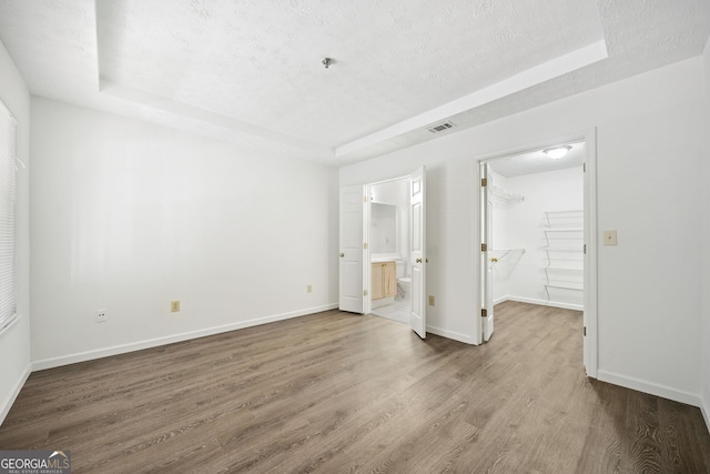 112 Bentley Pl, Tucker, GA 30084 - unfurnished bedroom featuring a textured ceiling, visible vents, wood finished floors, a tray ceiling, and a spacious closet
