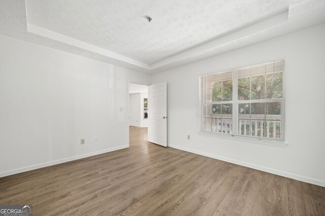 112 Bentley Pl, Tucker, GA 30084 - spare room featuring a raised ceiling, a textured ceiling, baseboards, and wood finished floors