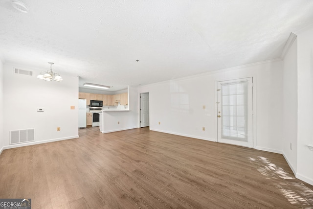 112 Bentley Pl, Tucker, GA 30084 - unfurnished living room featuring a textured ceiling, visible vents, crown molding, wood finished floors, and a notable chandelier