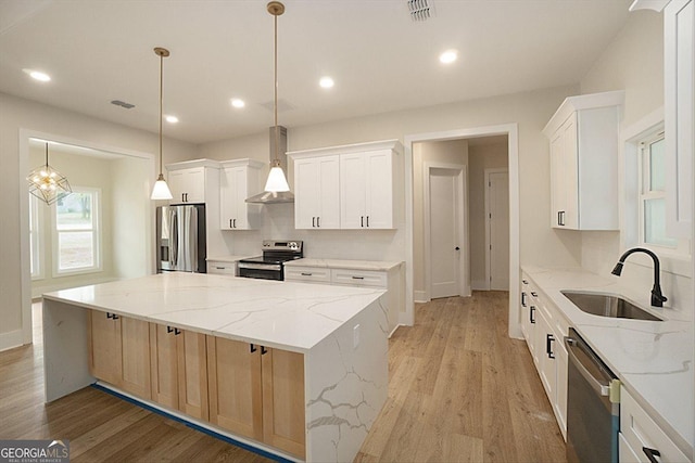 502 Camp Lake Rd, Monroe, GA 30655 - kitchen with appliances with stainless steel finishes, a sink, wall chimney range hood, a spacious island, and light wood-type flooring