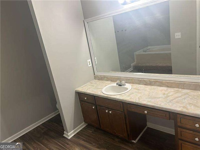 bathroom featuring baseboards, wood finished floors, vanity, and a tub to relax in