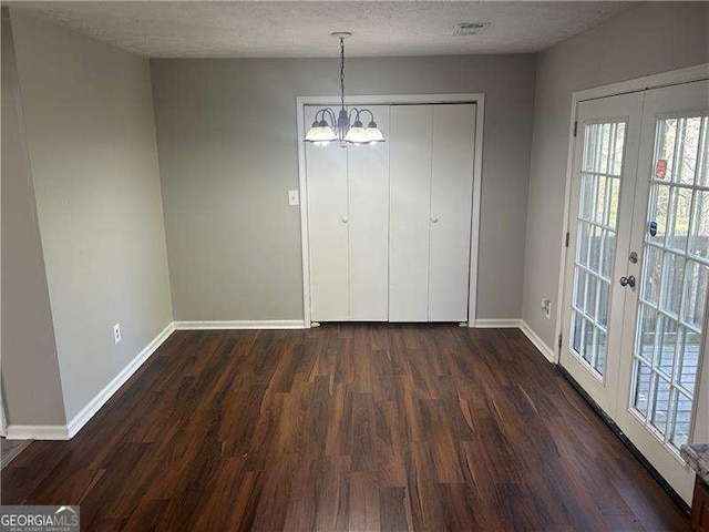 unfurnished dining area featuring dark wood finished floors, baseboards, french doors, and a textured ceiling