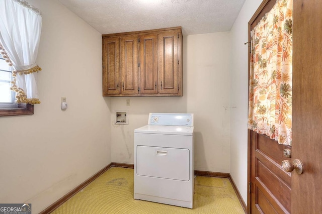 clothes washing area with baseboards, cabinet space, a textured ceiling, and washer / dryer