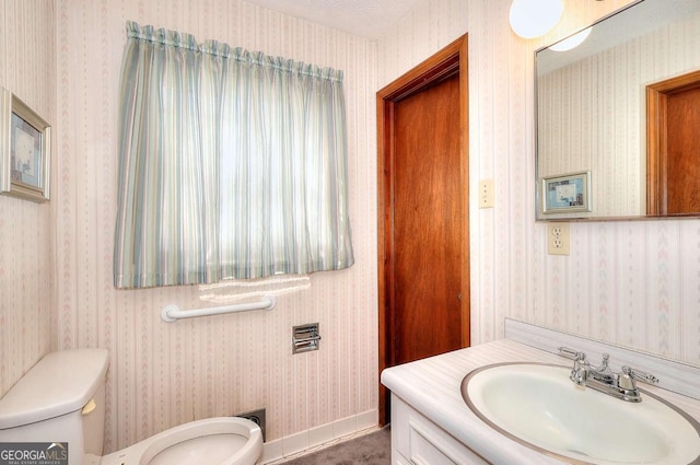 half bathroom featuring baseboards, wallpapered walls, toilet, and vanity