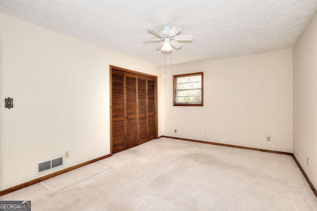 unfurnished bedroom with a closet, carpet flooring, a textured ceiling, visible vents, and baseboards