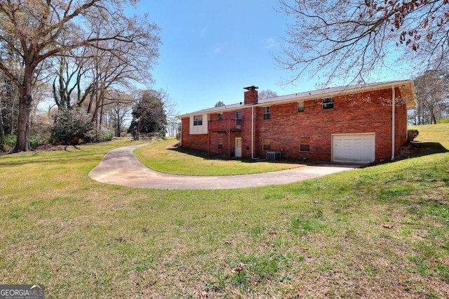 rear view of property with brick siding, a lawn, driveway, and a chimney