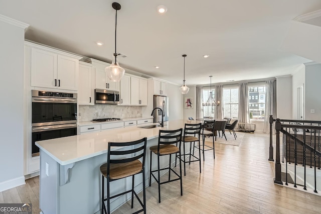 kitchen featuring tasteful backsplash, light wood-type flooring, light countertops, stainless steel appliances, and a spacious island