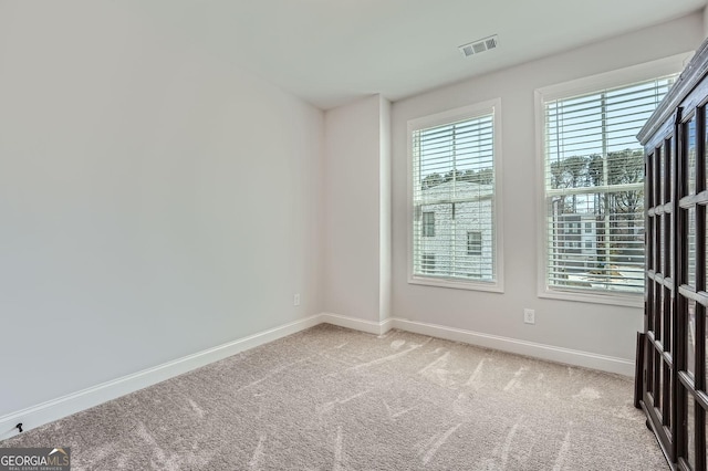 empty room with carpet flooring, baseboards, visible vents, and a wealth of natural light