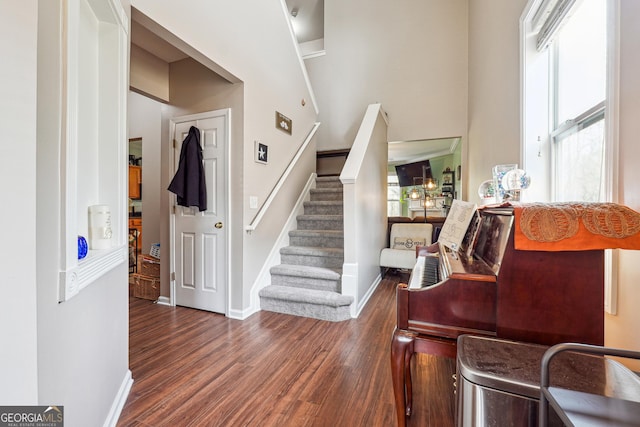 foyer entrance featuring baseboards, wood finished floors, and stairway