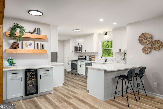 3069 Thrasher Cir, Decatur, GA 30032 - kitchen with wine cooler, stainless steel appliances, a peninsula, a breakfast bar, and light wood finished floors