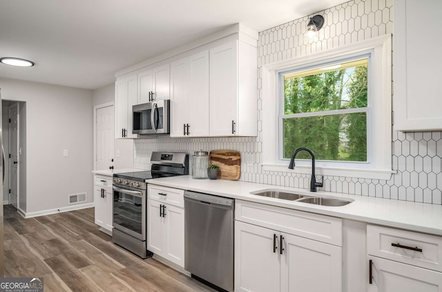 3069 Thrasher Cir, Decatur, GA 30032 - kitchen featuring stainless steel appliances, white cabinets, light countertops, backsplash, and wood finished floors