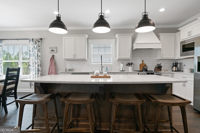kitchen featuring dark wood-type flooring, a kitchen island, ornamental molding, and premium range hood