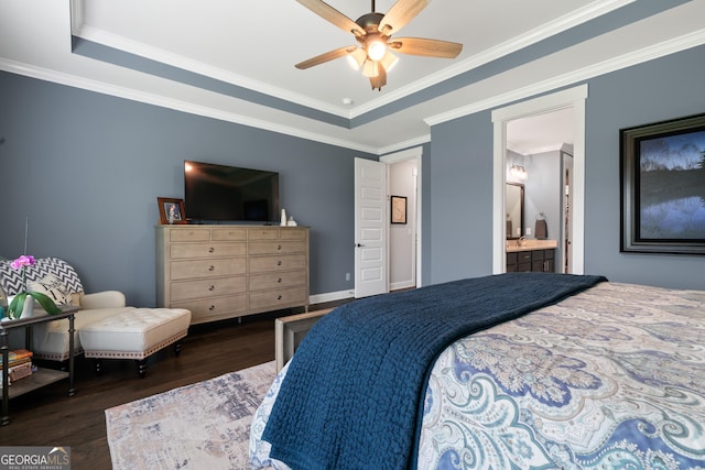 bedroom with a tray ceiling, wood finished floors, ensuite bathroom, baseboards, and ornamental molding