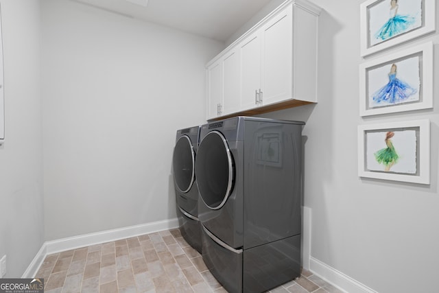 laundry room featuring washing machine and clothes dryer, cabinet space, and baseboards