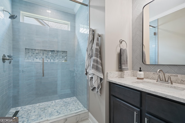 bathroom with vanity, ornamental molding, and tiled shower
