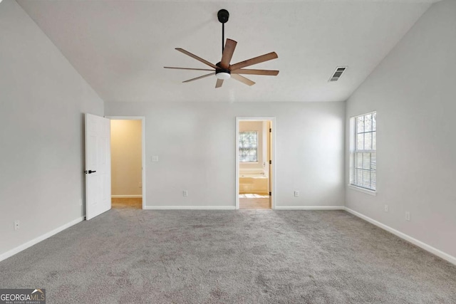 unfurnished bedroom with vaulted ceiling, baseboards, carpet floors, ensuite bath, and visible vents