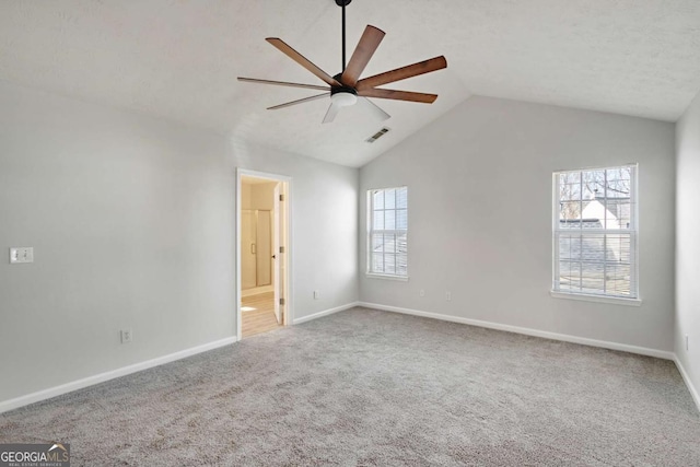 carpeted spare room featuring baseboards, vaulted ceiling, visible vents, and ceiling fan