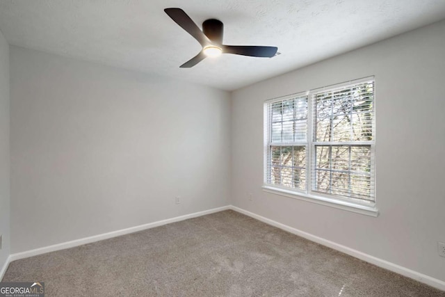 carpeted spare room with a ceiling fan and baseboards