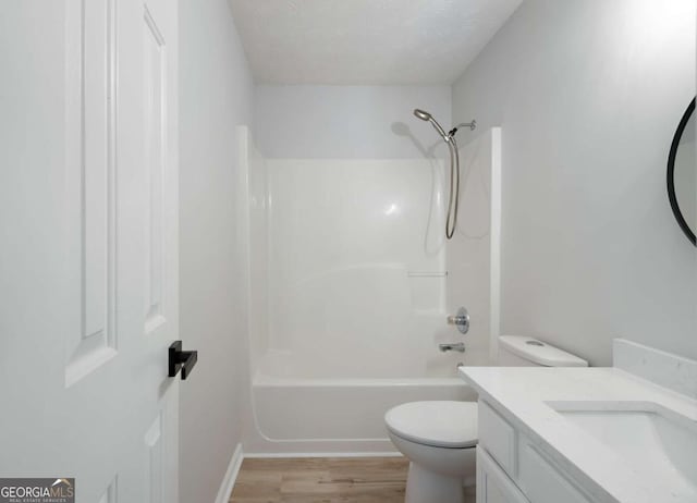 bathroom featuring a textured ceiling, wood finished floors, toilet, vanity, and shower / bathtub combination