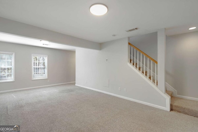 below grade area featuring baseboards, carpet floors, visible vents, and stairway