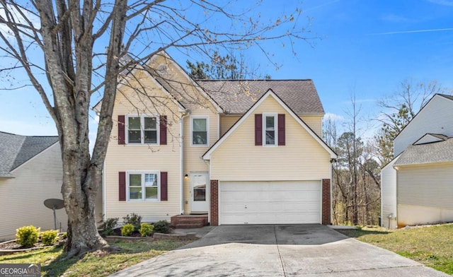 traditional-style home with roof with shingles, a garage, brick siding, and concrete driveway