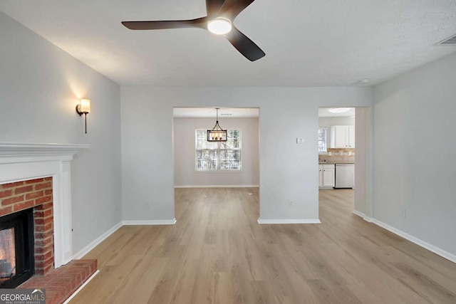 unfurnished living room with light wood-type flooring, baseboards, a fireplace, and ceiling fan