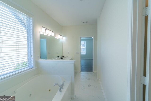 bathroom with a whirlpool tub, baseboards, marble finish floor, visible vents, and double vanity