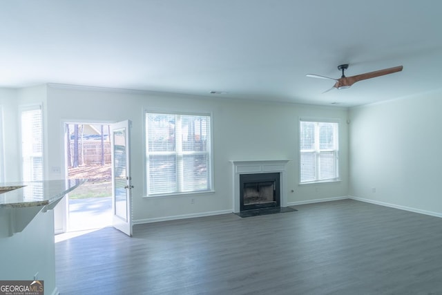 unfurnished living room with a fireplace with flush hearth, baseboards, wood finished floors, and ceiling fan
