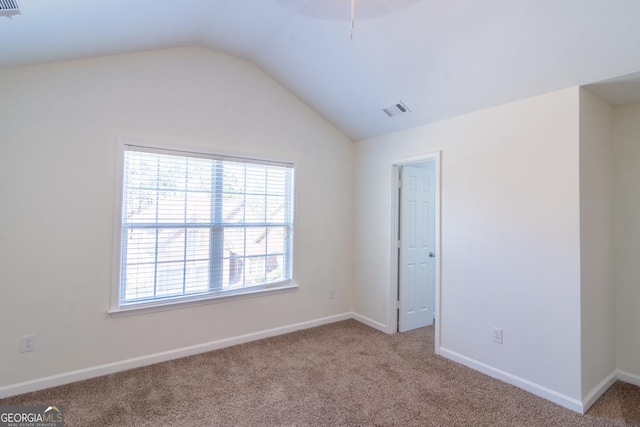unfurnished room featuring baseboards, carpet floors, visible vents, and vaulted ceiling