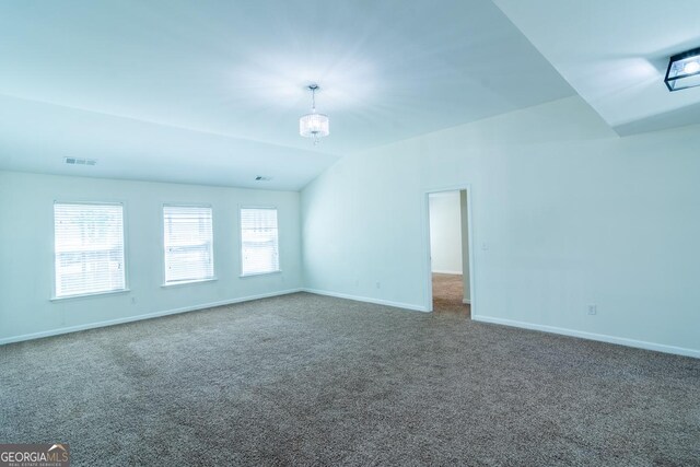 carpeted empty room featuring baseboards, visible vents, and vaulted ceiling