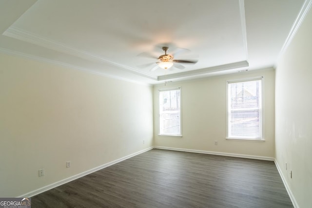 unfurnished room featuring a raised ceiling, dark wood-type flooring, baseboards, ceiling fan, and ornamental molding