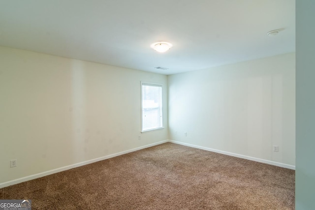 empty room featuring carpet floors, baseboards, and visible vents