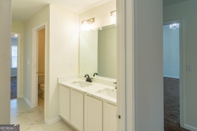 full bathroom featuring double vanity, toilet, baseboards, and a sink