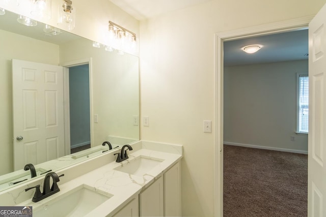 bathroom with baseboards, double vanity, and a sink