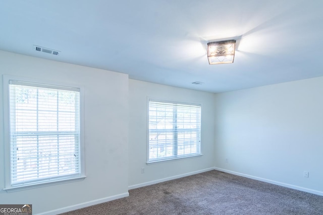empty room featuring baseboards, visible vents, and carpet floors