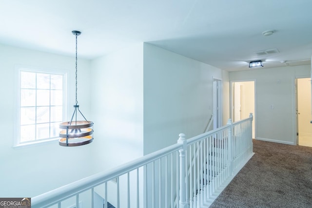corridor featuring baseboards, visible vents, an upstairs landing, and carpet