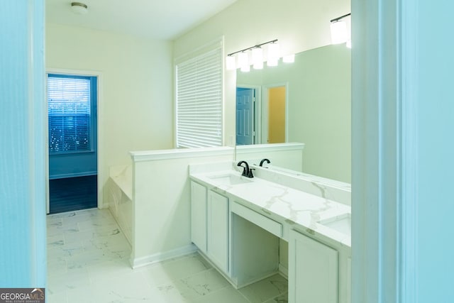 bathroom featuring marble finish floor, vanity, baseboards, and a garden tub