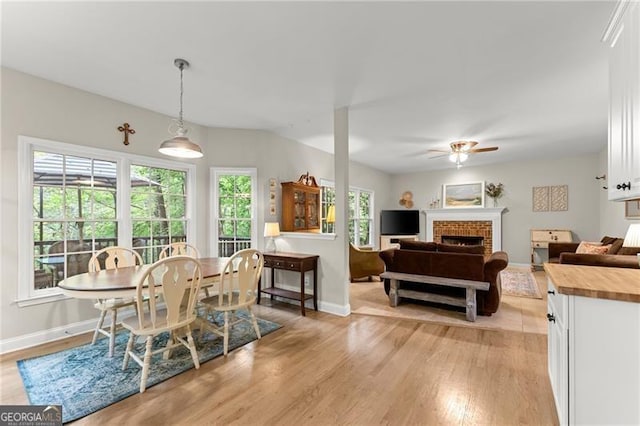 5055 Hamptons Club Dr, Alpharetta, GA 30004 - dining space with light wood-style flooring, a ceiling fan, and a brick fireplace