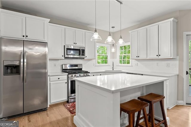 5055 Hamptons Club Dr, Alpharetta, GA 30004 - kitchen featuring appliances with stainless steel finishes, light wood-style flooring, white cabinets, and a kitchen island