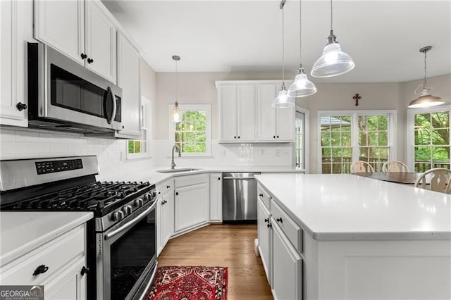 5055 Hamptons Club Dr, Alpharetta, GA 30004 - kitchen featuring stainless steel appliances, plenty of natural light, light wood finished floors, and a center island
