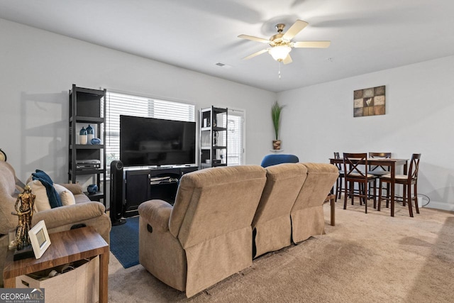 living area with light carpet, baseboards, visible vents, and ceiling fan