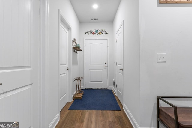 doorway featuring baseboards, visible vents, and dark wood-type flooring
