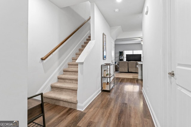hall featuring dark wood-style floors, stairway, and baseboards